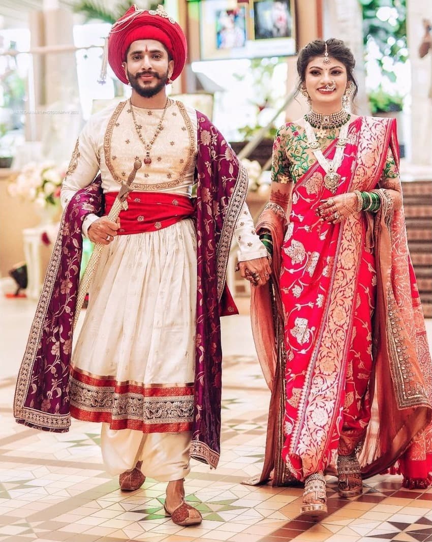 Bride and groom in royal Maratha wedding attire walking hand in hand
